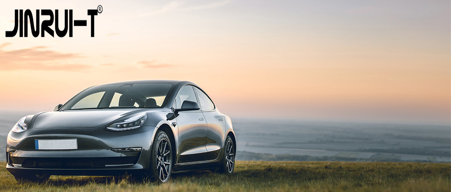Silver electric vehicle photographed at sunset against a scenic horizon, showcasing sleek aerodynamic design and sporty profile.