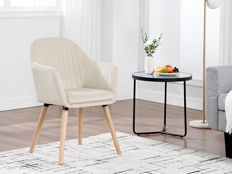 de color crema con respaldo acolchado en forma de canal, brazos curvos y patas de madera, que se muestra junto a una mesa auxiliar redonda negra