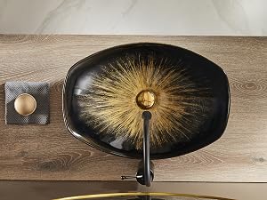 Plato decorativo ovalado negro con llamativo patrón de rayos solares dorados desde el centro, sobre una superficie de madera.