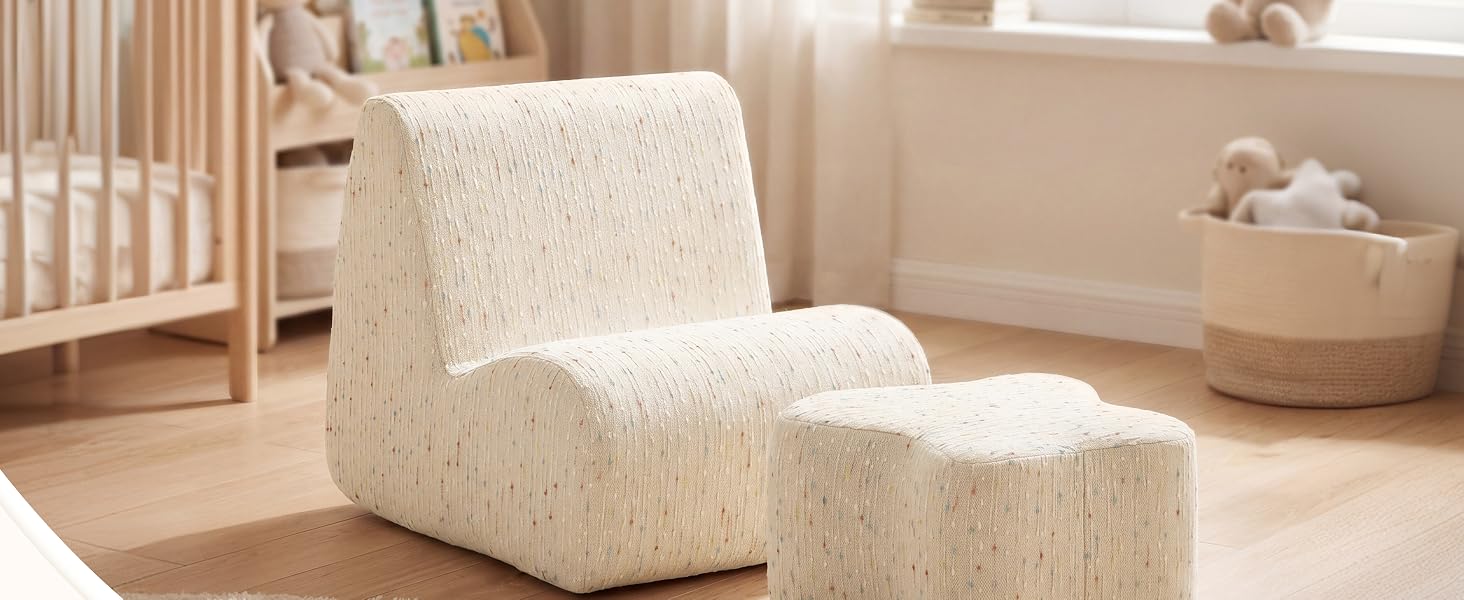 Poltrona imbottita testurizzata color crema con poggiapiedi pouf abbinato nella stanza dei bambini minimalista con culla e cestini portaoggetti intrecciati a vista.