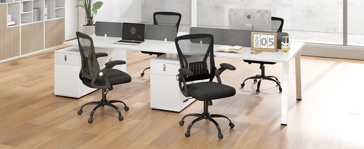Modern office workspace with two black mesh ergonomic office chairs, white desk with computer monitor, wooden flooring, and large windows with natural lighting in contemporary office setting.
