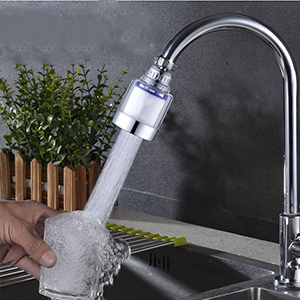 Kitchen faucet attachment with transparent filter housing, spraying aerated water. Demonstrates water-saving function with visible bubbles in the stream.