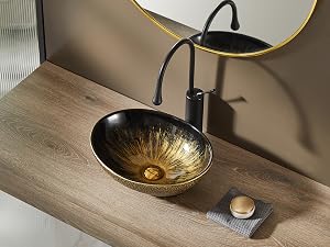Lavabo ovalado dorado‑negro sobre encimera de madera con grifo negro. Encima se ve un espejo redondo con borde dorado.