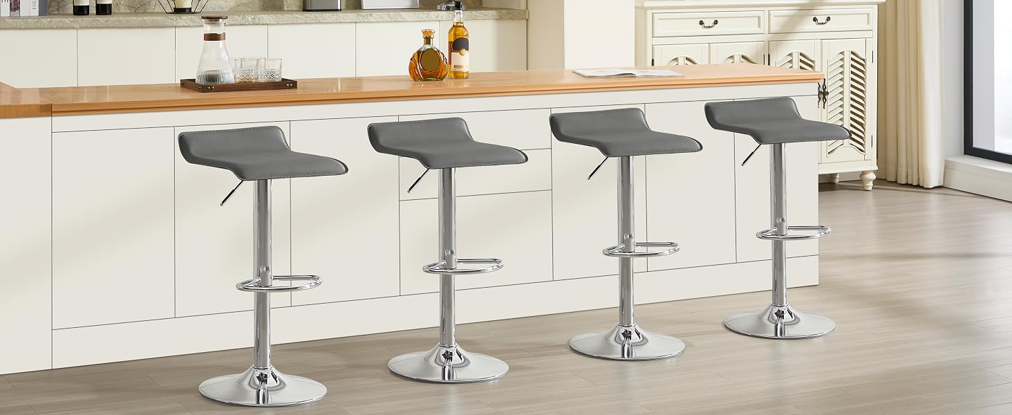 Four modern adjustable bar stools with grey seats and chrome bases arranged along a white kitchen counter island.