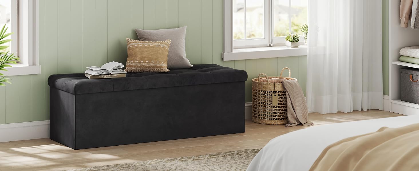 Panca portaoggetti imbottita nera con piano capitonné posta ai piedi di un letto. Dispone di un coperchio ribaltabile per riporre gli oggetti all'interno. Cuscini decorativi visibili