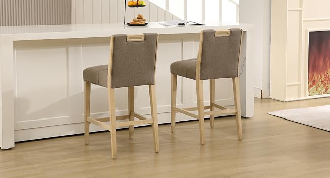 Two beige upholstered bar stools with wooden legs positioned at white kitchen counter or island.
