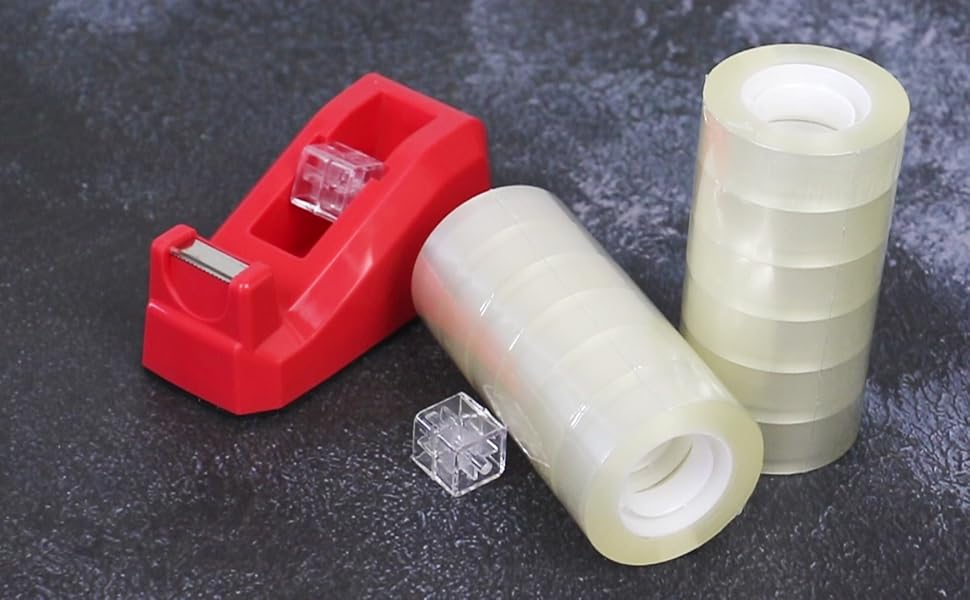 Red tape dispenser with clear rolls of adhesive tape and stack of transparent tape rolls on dark surface.