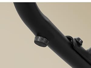 Objeto cilíndrico negro con sección de agarre con textura acanalada y componente moldeado oscuro visible sobre un fondo beige neutro. Captura detallada en primer plano del mecanismo o punto de fijación del producto.