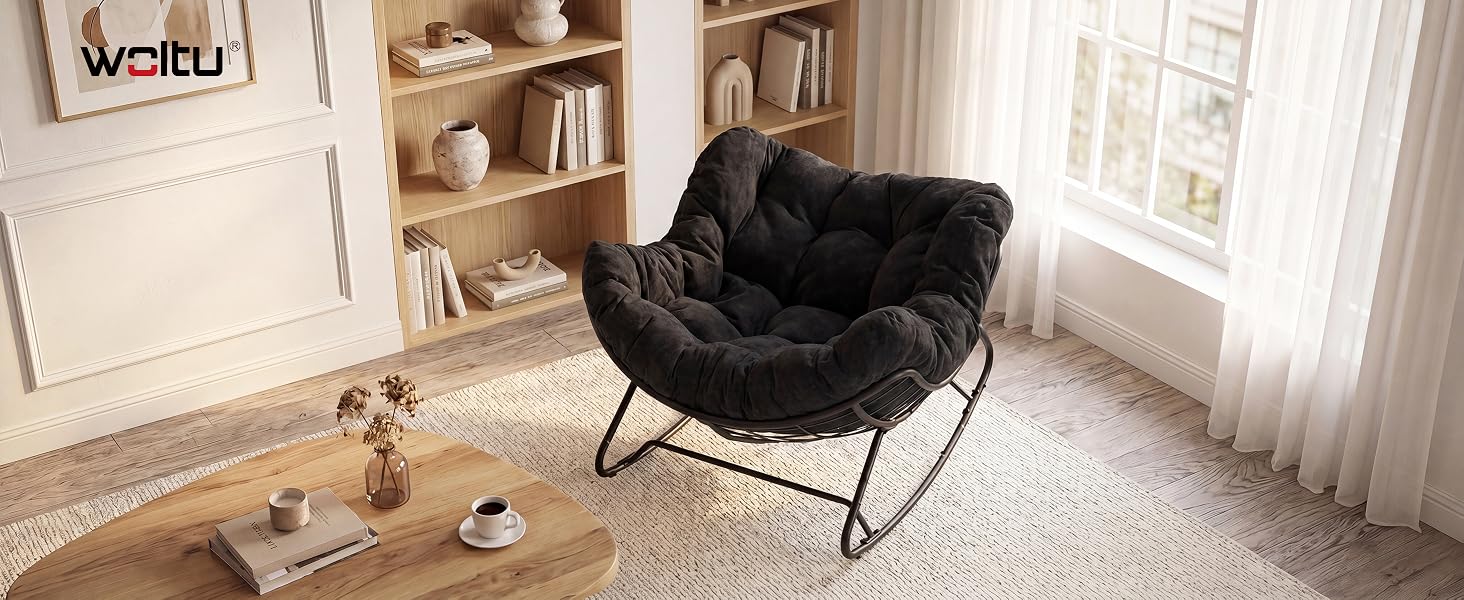Chaise papasan noire ou chaise rembourrée ronde avec structure en métal dans un intérieur de maison moderne avec étagères blanches, parquet et fenêtre avec rideaux.
