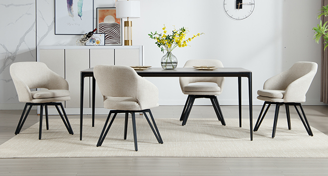 Moderne Essgruppe mit rechteckigem schwarzem Tisch und vier cremefarbenen Polsterstühlen. Die Stühle haben eine geschwungene Rückenlehne und schwarze Metallbeine. Weißes Sideboard und Dekor im Hintergrund