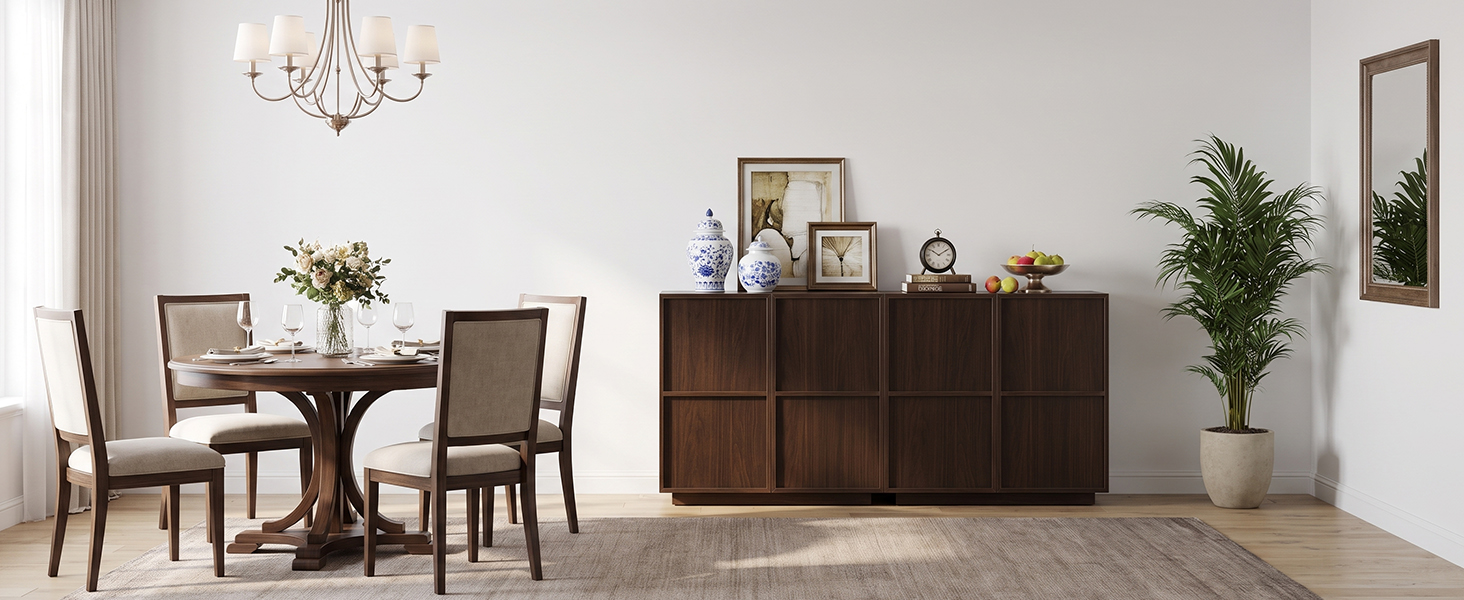 Image d'aménagement intérieur montrant une table à manger avec des chaises, une commode en bois avec des objets décoratifs, des murs blancs, un lustre et des plantes en pot dans une pièce lumineuse et minimaliste.