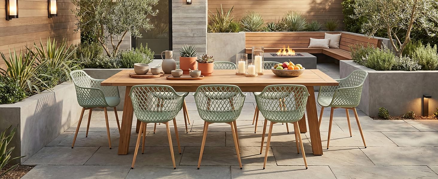 Configuration de salle à manger extérieure avec table en bois, chaises vert menthe et tables disposées sur le patio avec un aménagement paysager du jardin en arrière-plan.