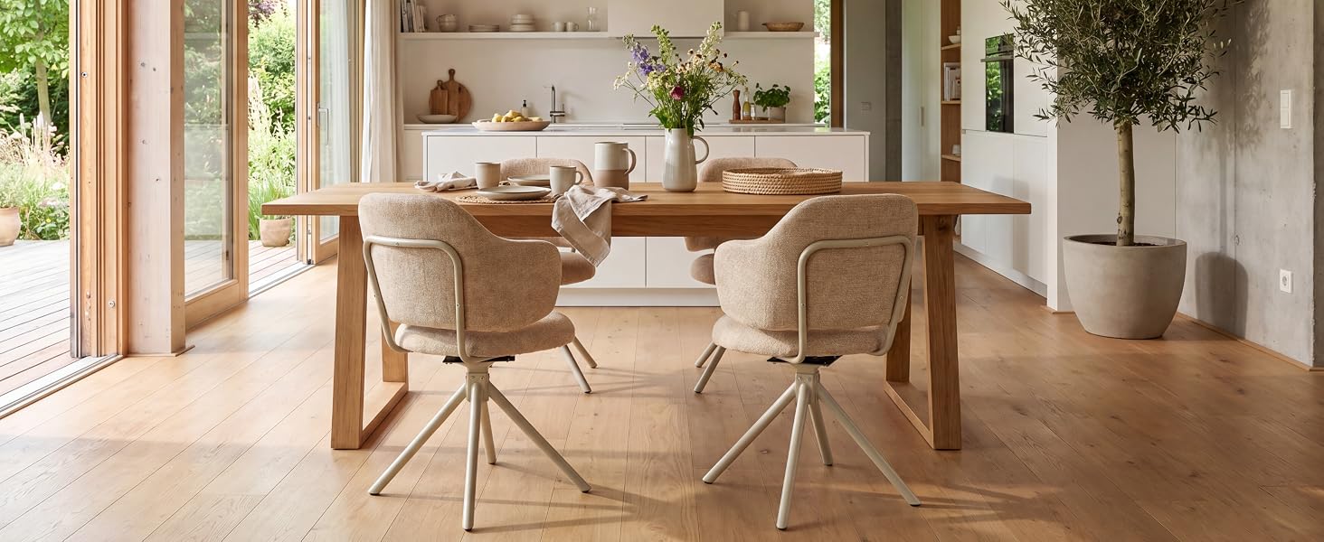 Intérieur de la salle à manger moderne avec table en bois clair, chaises en rotin tressé, parquet chaud et grandes portes vitrées donnant sur le jardin.