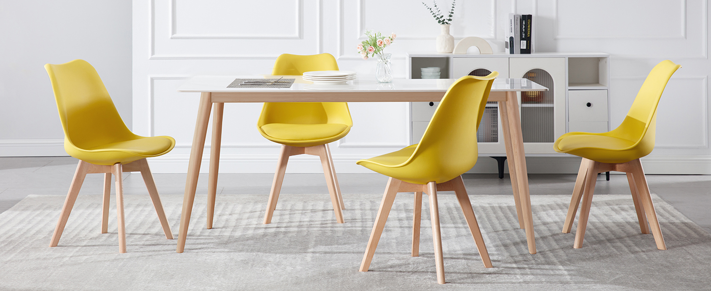 con mesa rectangular blanca y seis sillas amarillas de plástico moldeado con patas de madera. Ambiente minimalista de habitación blanca.