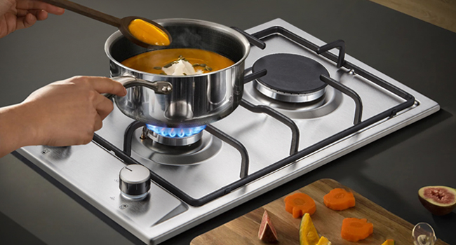 Images séquentielles d'un brûleur de cuisinière à gaz allumé et réglé, montrant une flamme bleue à différentes intensités sur une surface de cuisson en acier inoxydable.