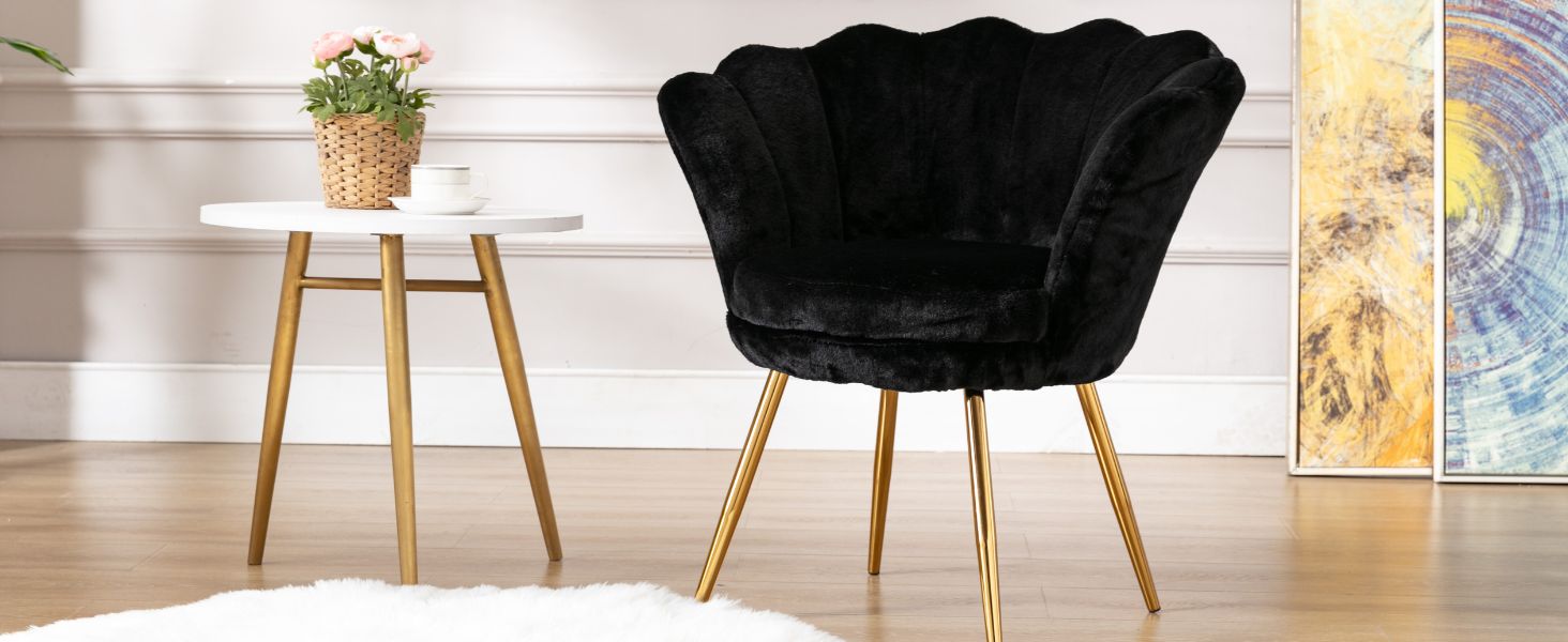 Stuhl aus schwarzem Samt mit gewellter Rückenlehne und goldfarbenen Metallbeinen. Weißer Beistelltisch mit Holzbeinen. Topfpflanze auf dem Tisch. Abstrakte Kunst im Hintergrund