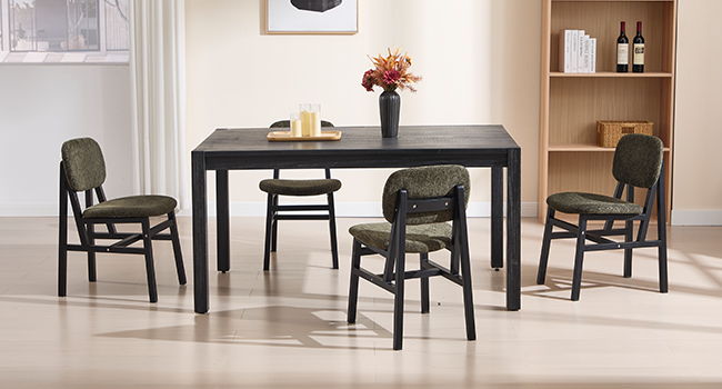Moderna sala da pranzo con tavolo in legno scuro e quattro sedie nere, scaffale in legno visibile contro una parete bianca con composizione floreale.
