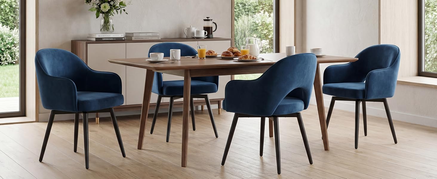 Set da pranzo moderno con tavolo in legno naturale e quattro sedie imbottite blu con gambe nere in un luminoso spazio abitativo contemporaneo con sfondo di scrivania in legno.