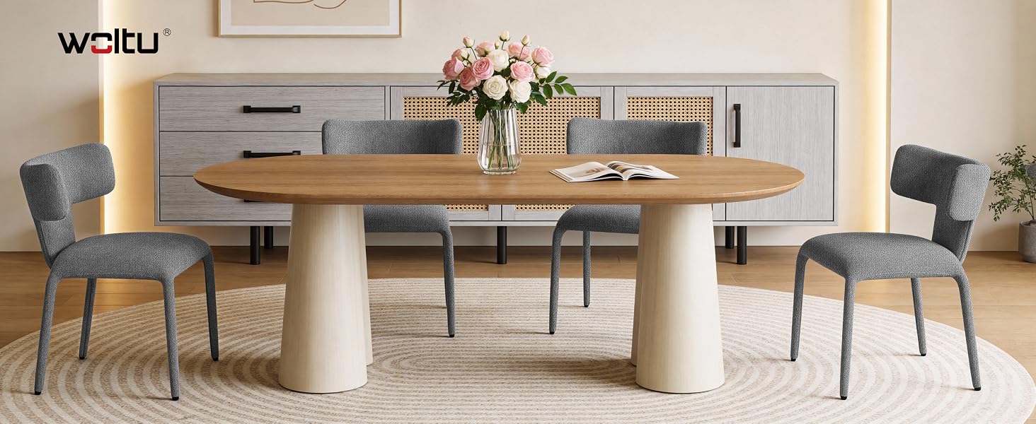 Set da pranzo moderno con tavolo ovale in legno con due basi a piedistallo in cemento, accompagnato da sedie imbottite grigie. Al centro del tavolo c'è un vaso decorativo con fiori.