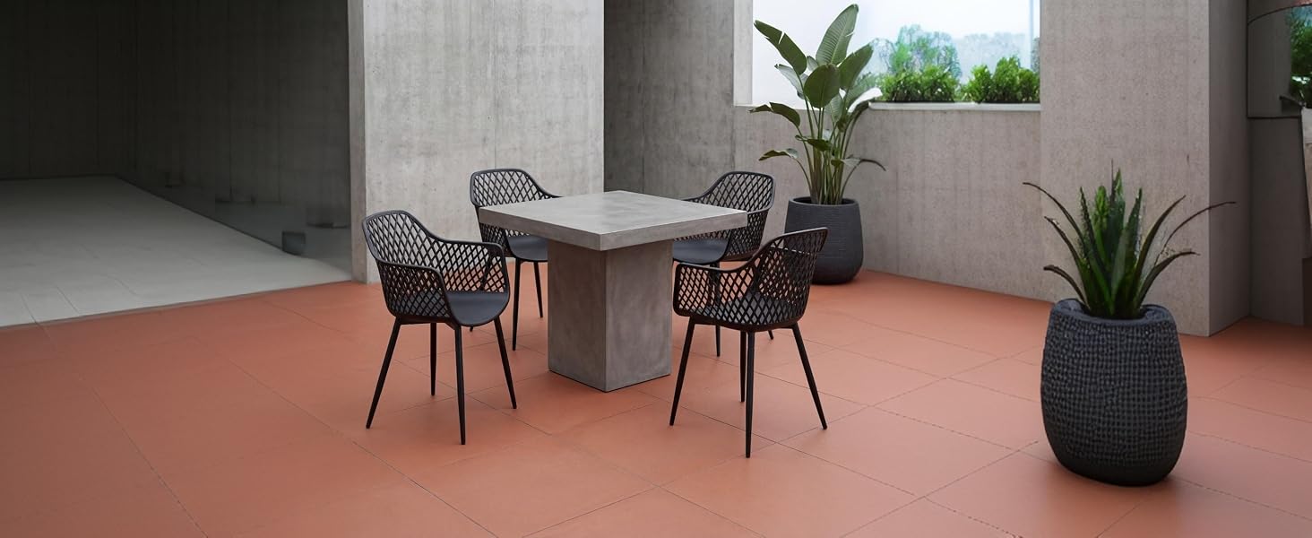 Espace intérieur moderne avec une table ronde, deux chaises foncées, des plantes en pot et un sol aux tons neutres. Aménagement de mobilier contemporain minimaliste pour un bureau ou une réunion.
