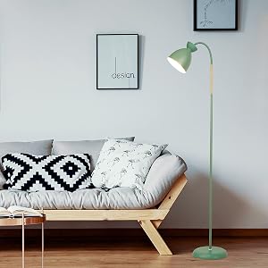 Mintgrüne Stehlampe mit verstellbarem Kopf neben einem Tagesbett mit Holzrahmen, grauem Kissen und gemusterten