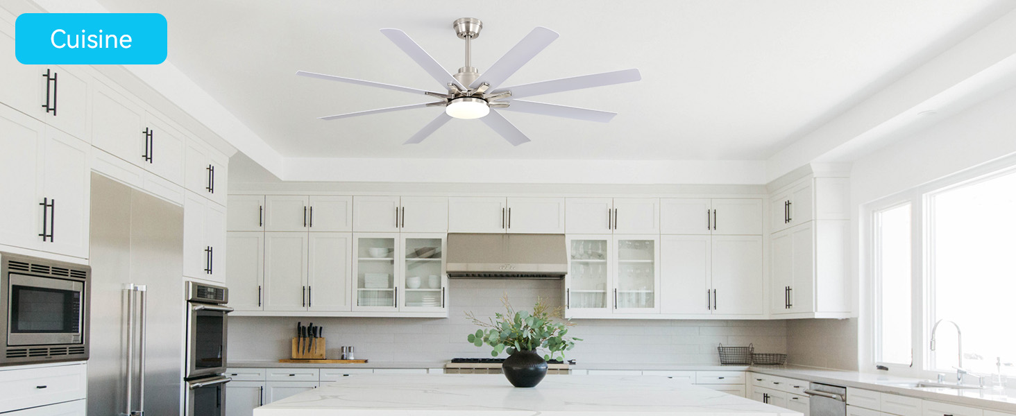 Le texte indique « Cuisine ». Intérieur de cuisine blanc moderne avec ventilateur de plafond, armoires blanches, appareils électroménagers en acier inoxydable et éclairage naturel brillant provenant des fenêtres.