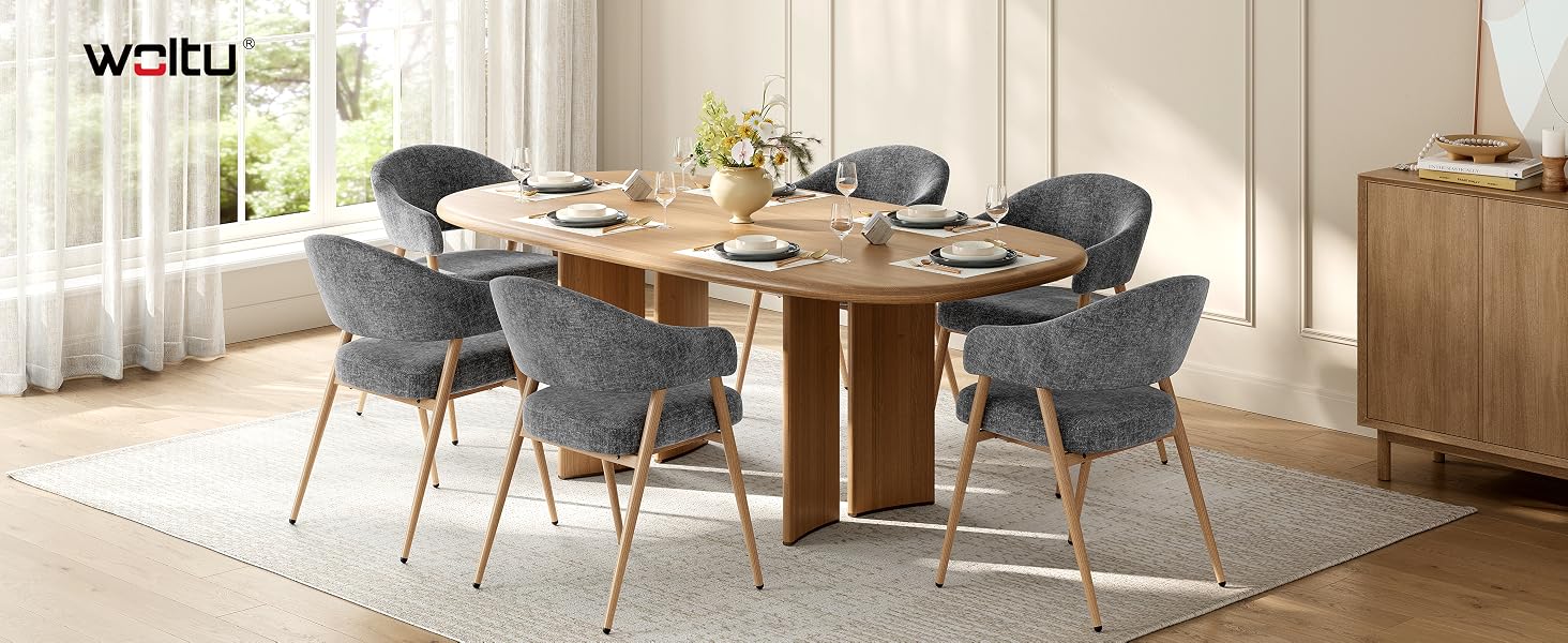 Der Text lautet „Watu“. Modernes Esszimmer mit Holztisch, gepolsterten Stühlen, Pendelleuchte und dekorativen Pflanzen in neutralen Farbtönen.