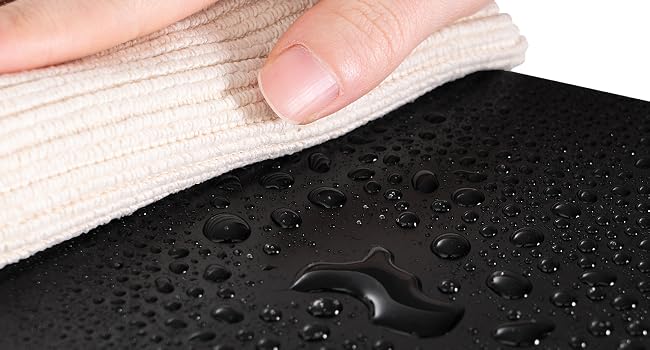 una persona que limpia una superficie de goma negra con gotas de agua