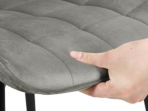Close-up of quilted grey chair cushioning being pressed to demonstrate padding thickness and texture.