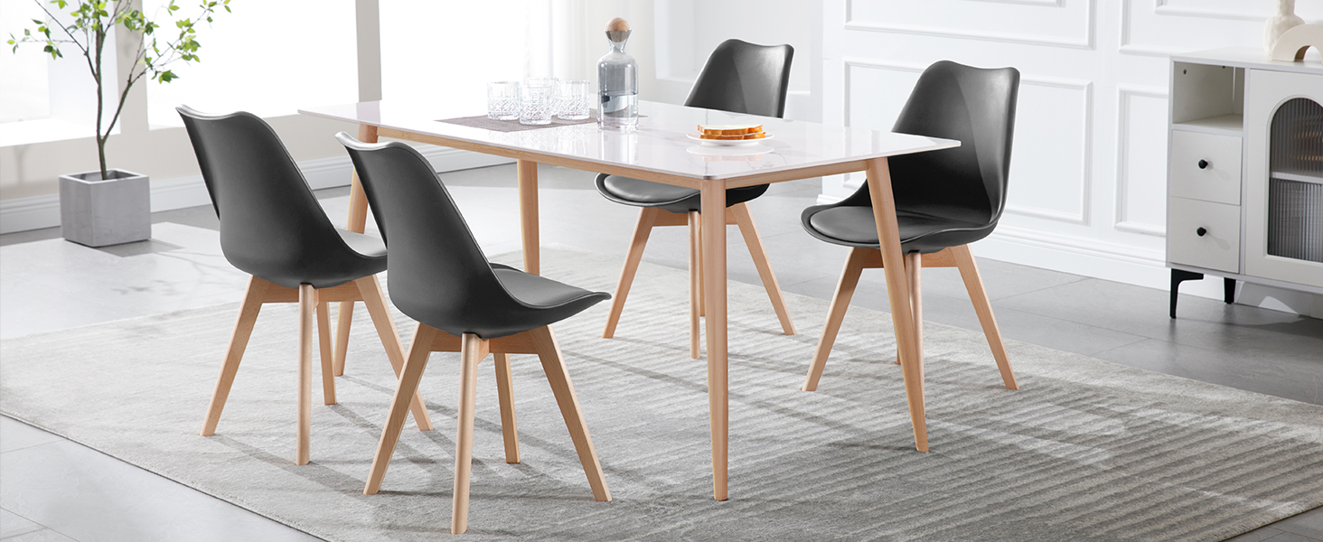 Modern dining set with white rectangular table and four black molded chairs featuring wooden legs, arranged on light flooring against white walls.