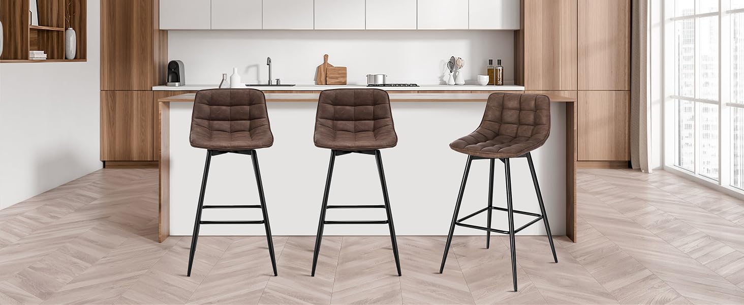 Three brown upholstered bar stools with tufted backs and metal legs, positioned at a white kitchen island in a modern wooden kitchen.