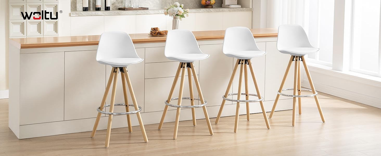 Cuatro taburetes de bar modernos blancos con patas de madera en un entorno de cocina. Los taburetes tienen asientos curvos y bases triangulares. En el fondo se ve una encimera de cocina