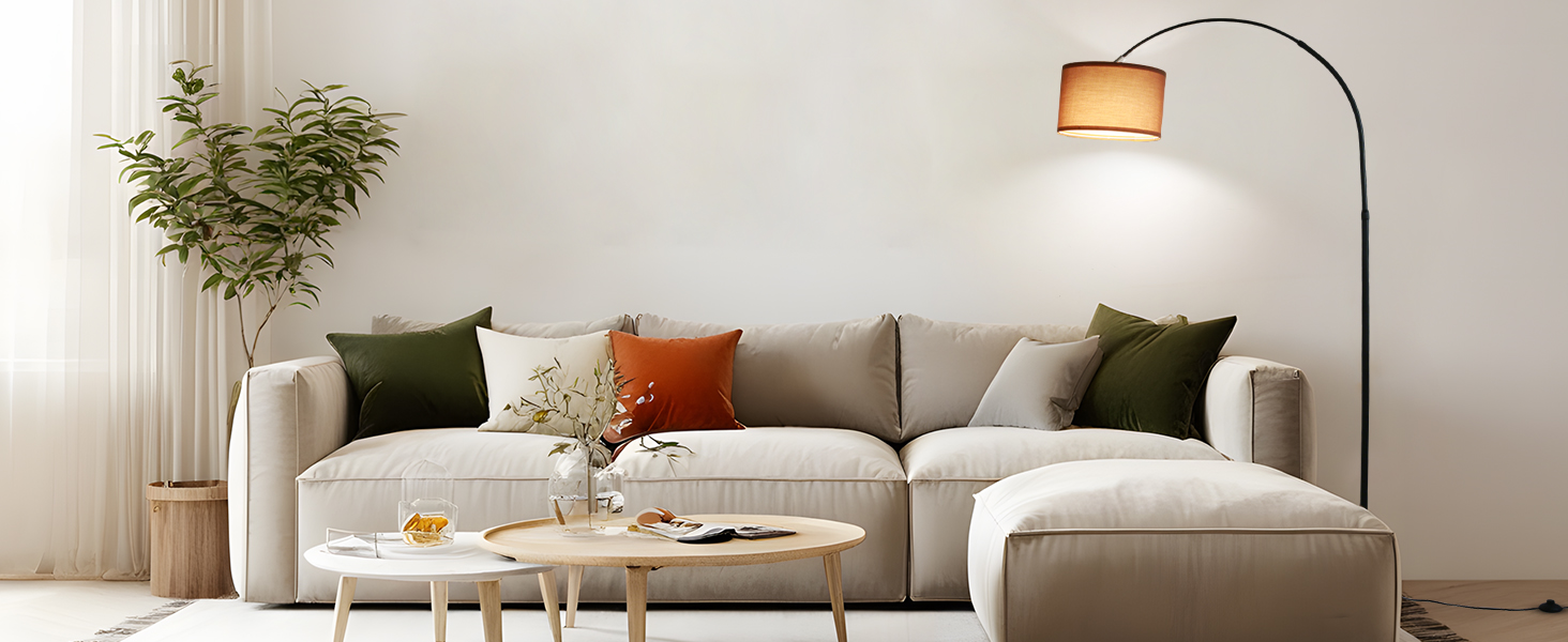 Modernes Wohnzimmer mit L-förmigem beigem Ecksofa, Bogenstehlampe, Couchtischen aus Holz und dekorativen Kissen in Grün und Orange. Die Topfpflanze in der Ecke sorgt für eine natürliche Note