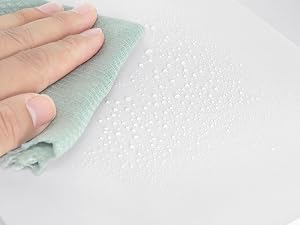 Pulire a mano una superficie bianca con un panno verde chiaro, dimostrando proprietà resistenti all'acqua o