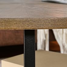 Close-up of a wooden table edge, showing laminated wood top and black metal leg, part of a modern furniture piece.