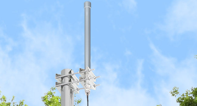 Cellular tower equipment mounted on a tall metal pole against a blue sky with clouds. Multiple antenna arrays visible at the top of the structure.