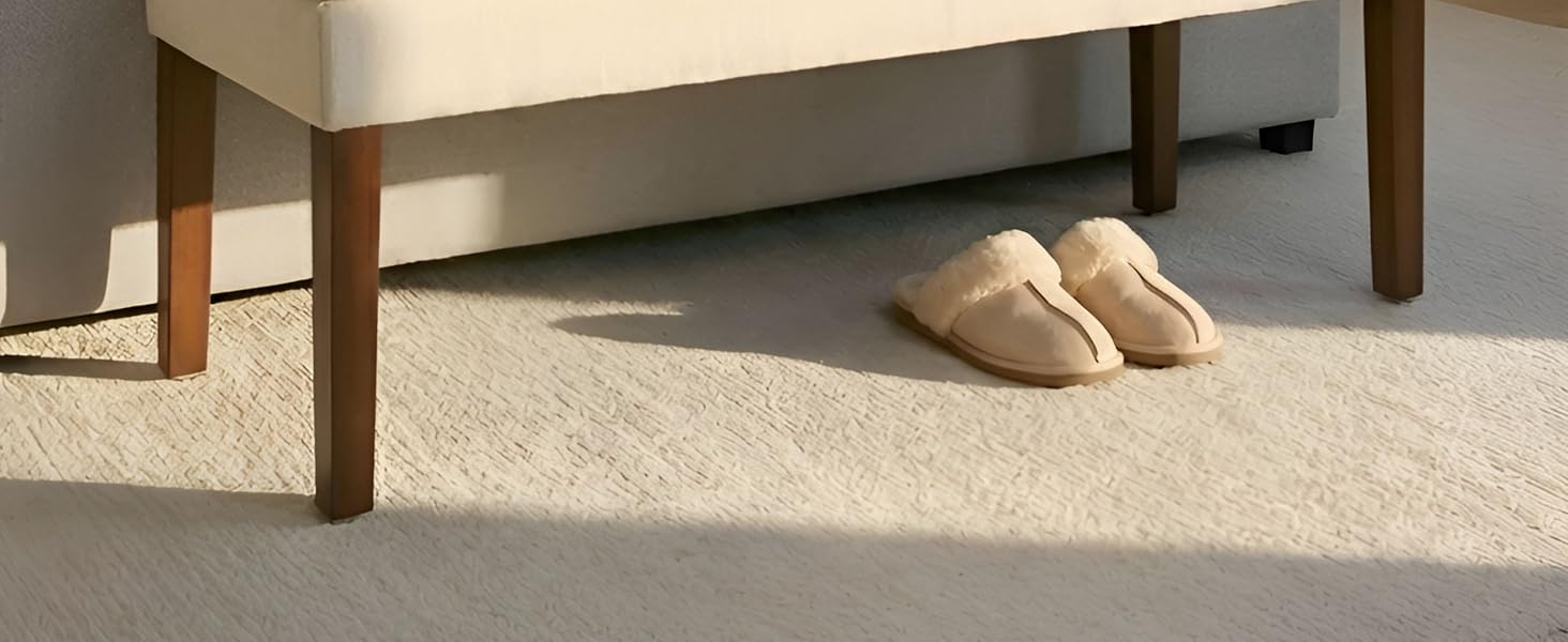 Vue en angle d'une pièce revêtue de moquette de couleur crème avec pieds de meubles en bois visibles. Montre la texture du sol et les détails de l'intérieur de la pièce.