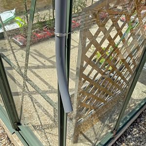 Close-up of window or door track mechanism showing metal rails and latticed screen pattern in background.
