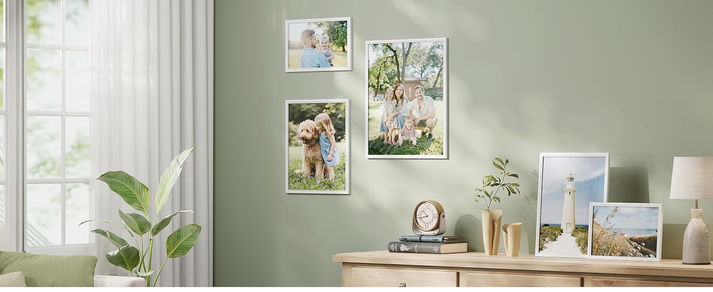 Vetrina di interior design caratterizzata da pareti verde chiaro con più immagini incorniciate disposte in stile galleria, accanto a piante decorative e mobili.