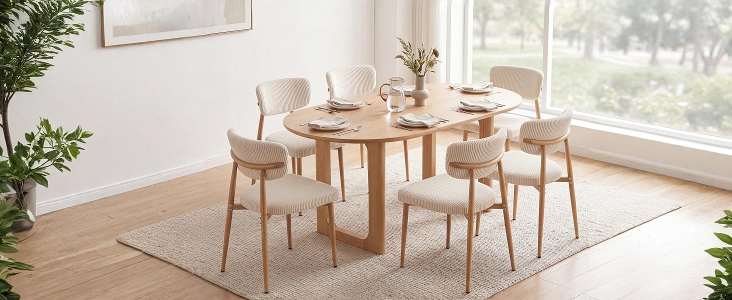 Ensemble de salle à manger moderne en bois avec table et chaises en bois naturel positionnées près de grandes fenêtres laissant entrer la lumière du jour et laissant apparaître des plantes en pot.