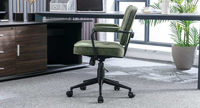 Green upholstered office chair with armrests and wheeled base, positioned in a modern office setting with wood cabinets and carpet visible.