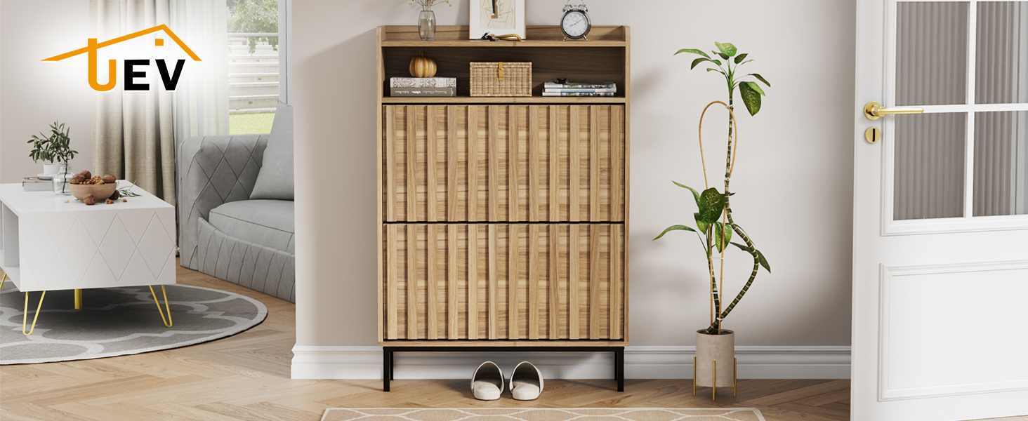 Il testo dice «EV». Ingresso moderno con scarpiera in legno con doghe verticali, pareti bianche e piante decorative.