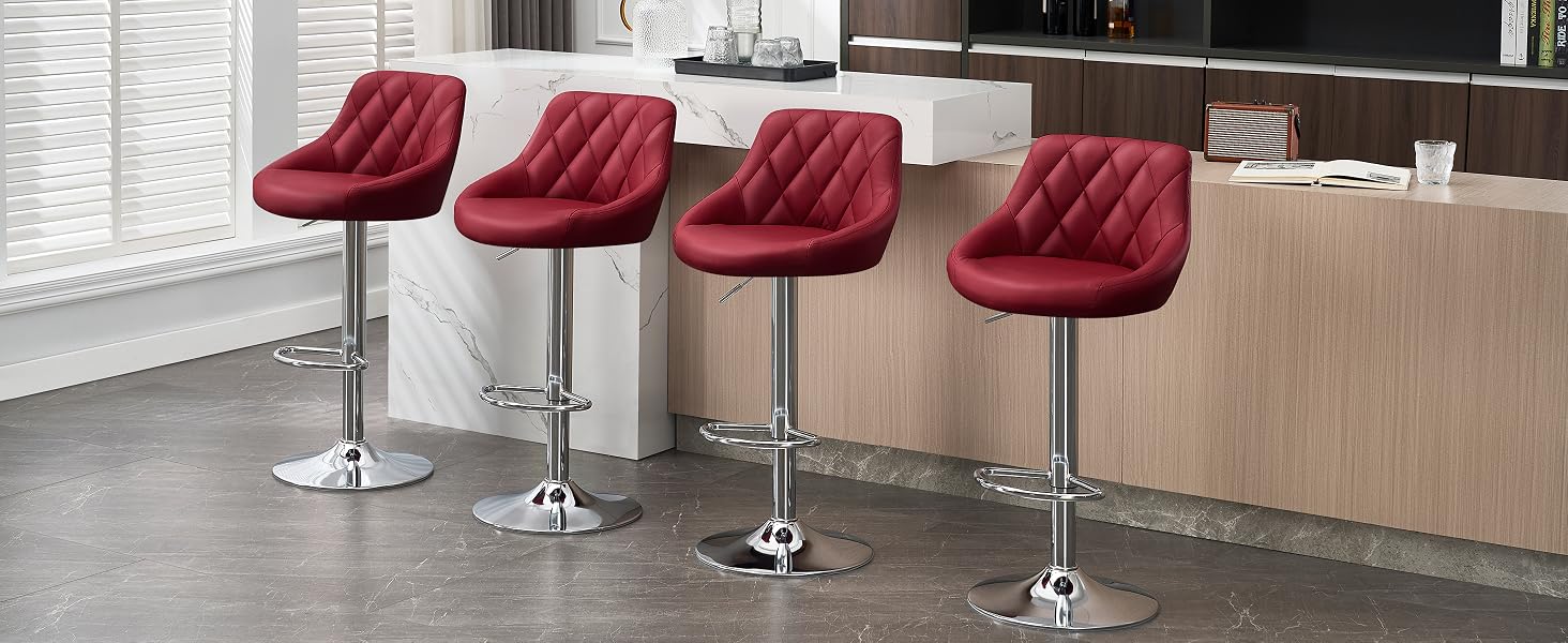 Cuatro taburetes de bar de cuero rojo con respaldos capitonados y bases cromadas, dispuestos en fila a lo largo de la encimera de la cocina. Los taburetes cuentan con altura ajustable y