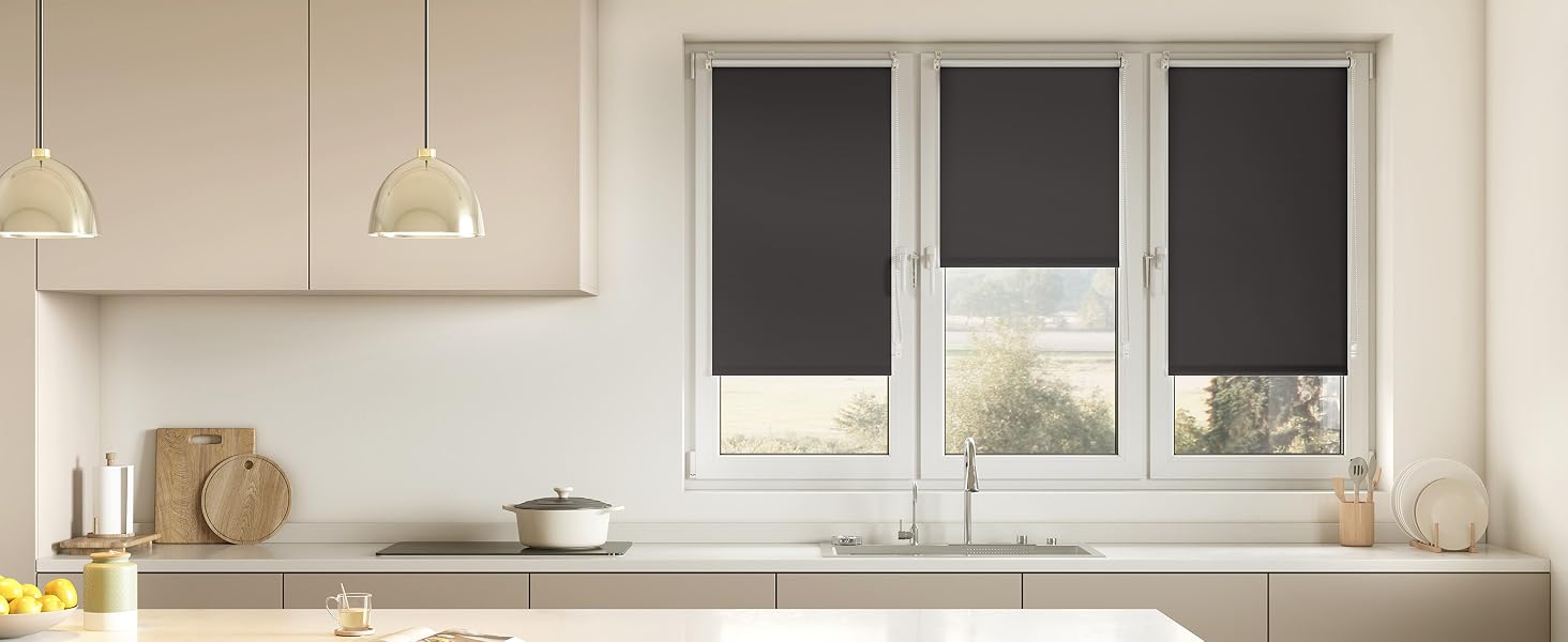 Interior de cocina moderno con tres persianas enrollables negras montadas en las ventanas.
[SENTENCE 17] Encimeras y gabinetes de color beige visibles con luces colgantes en la parte superior.