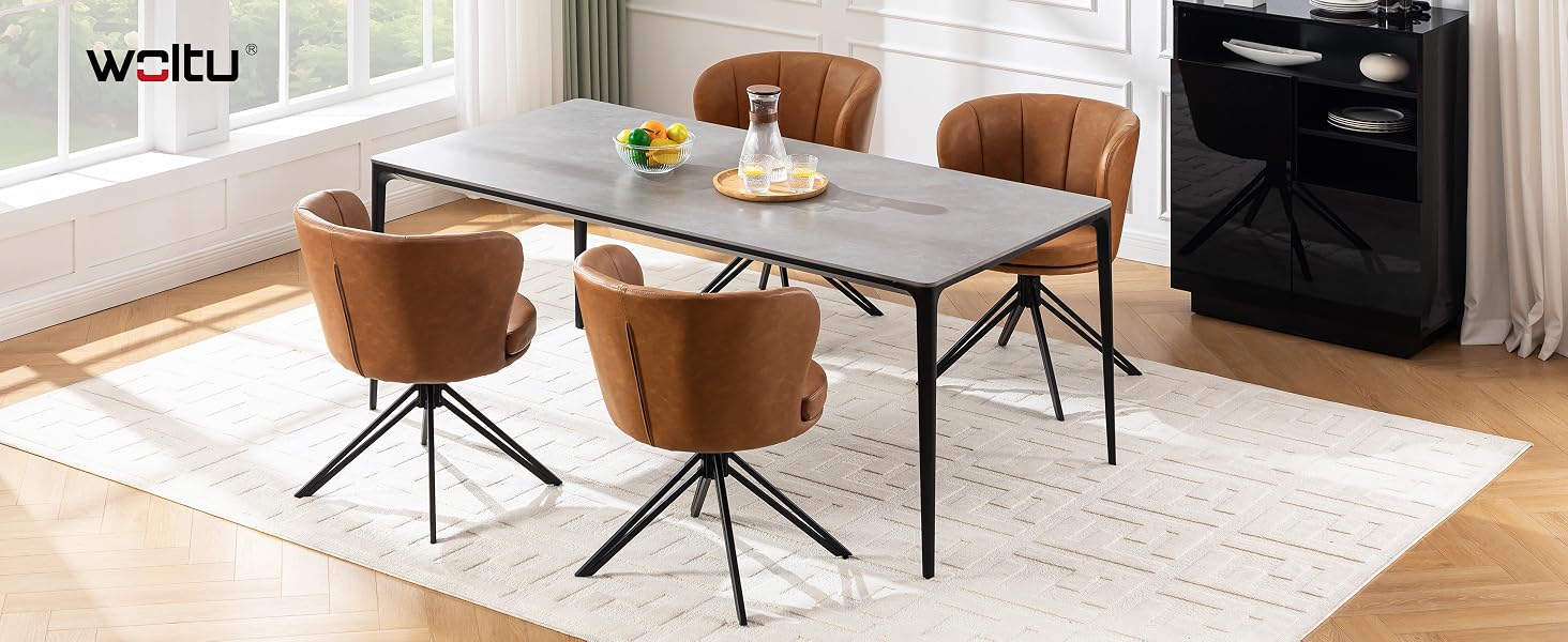 Área de comedor moderna con una gran mesa rectangular con tapa de color claro y patas de metal negro, rodeada de sillas de comedor de cuero marrón sobre una alfombra clara.