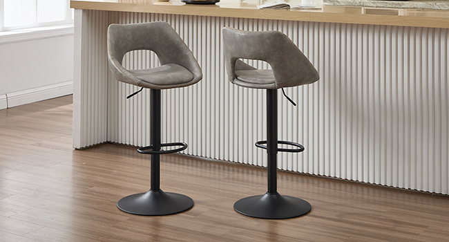 Two modern gray upholstered adjustable bar stools with curved backrests and black metal bases, positioned at a white kitchen island with corrugated panel detail.