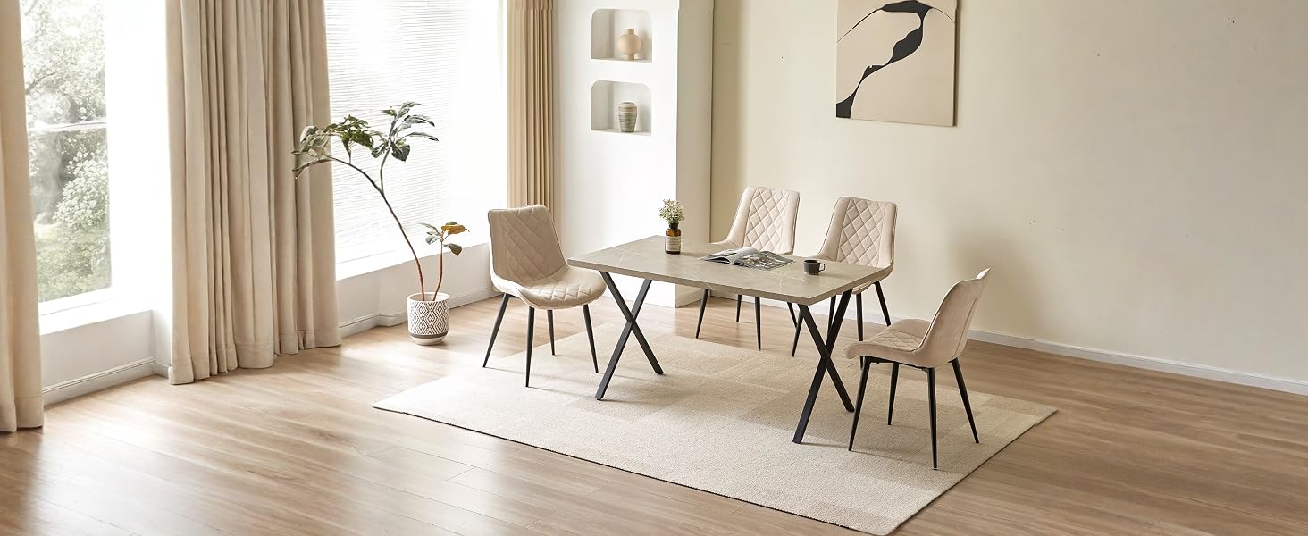 Salle à manger moderne avec table en bois clair, quatre chaises rembourrées beiges, grandes fenêtres avec rideaux crème et décoration murale minimaliste sur des murs neutres.