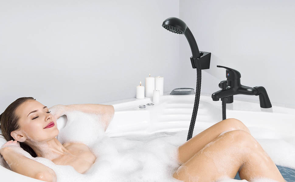 Black handheld shower head with mount shown installed on a white bathtub. Decorative white candles visible in the background.