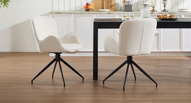 Modern dining area featuring white upholstered chairs with black metal spider base legs, positioned at a dark table.