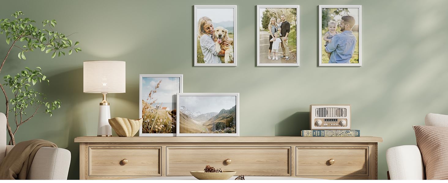 Espositore da parete da galleria in soggiorno che mostra più fotografie incorniciate disposte su una parete verde chiaro, con lampada da tavolo e decorazioni visibili.